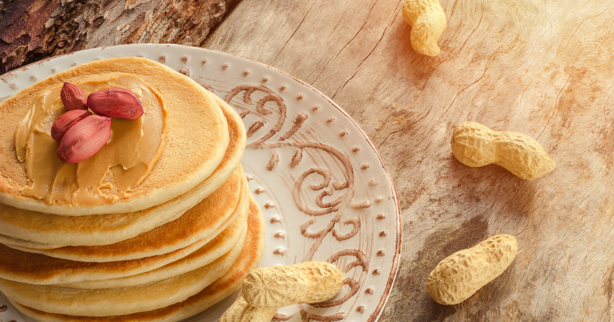 A stack of pancakes with peanut butter and syrup on a plate.