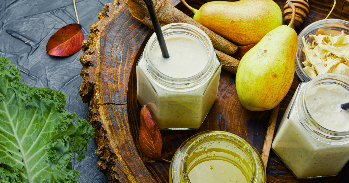 A wooden cutting board topped with jars of food and a spoon.