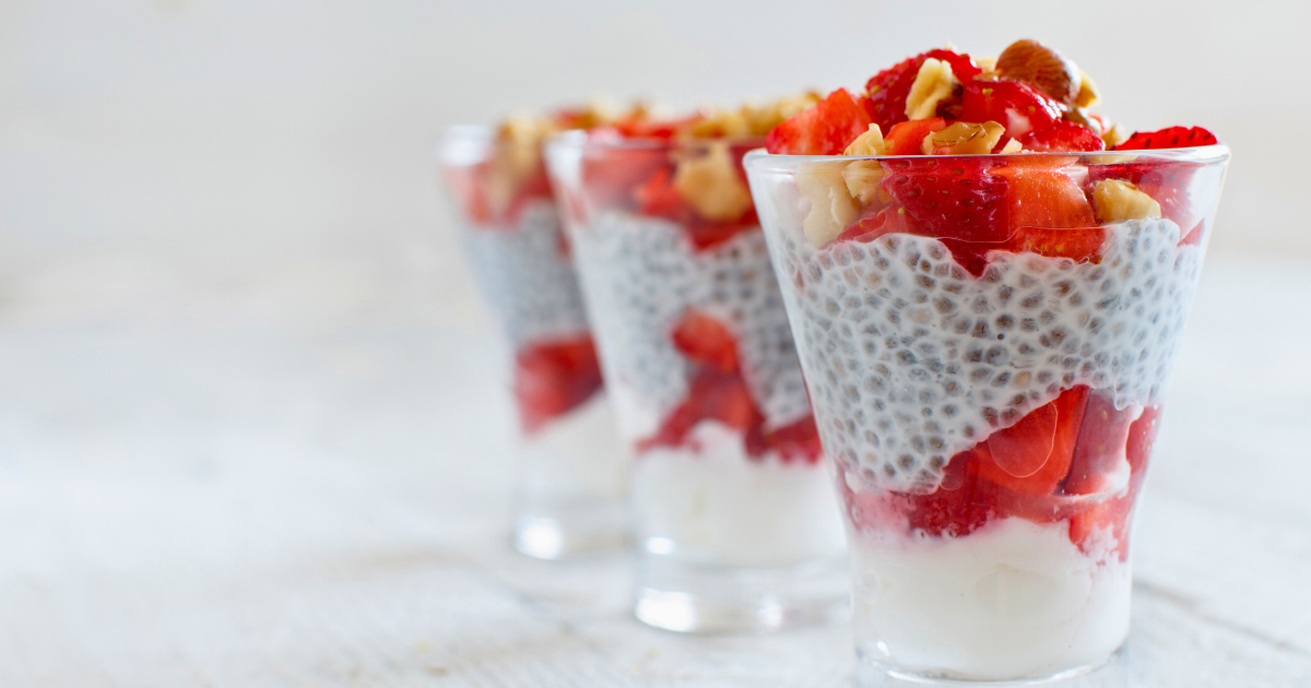 Three glasses filled with strawberries  and chia seeds  pudding on a table.