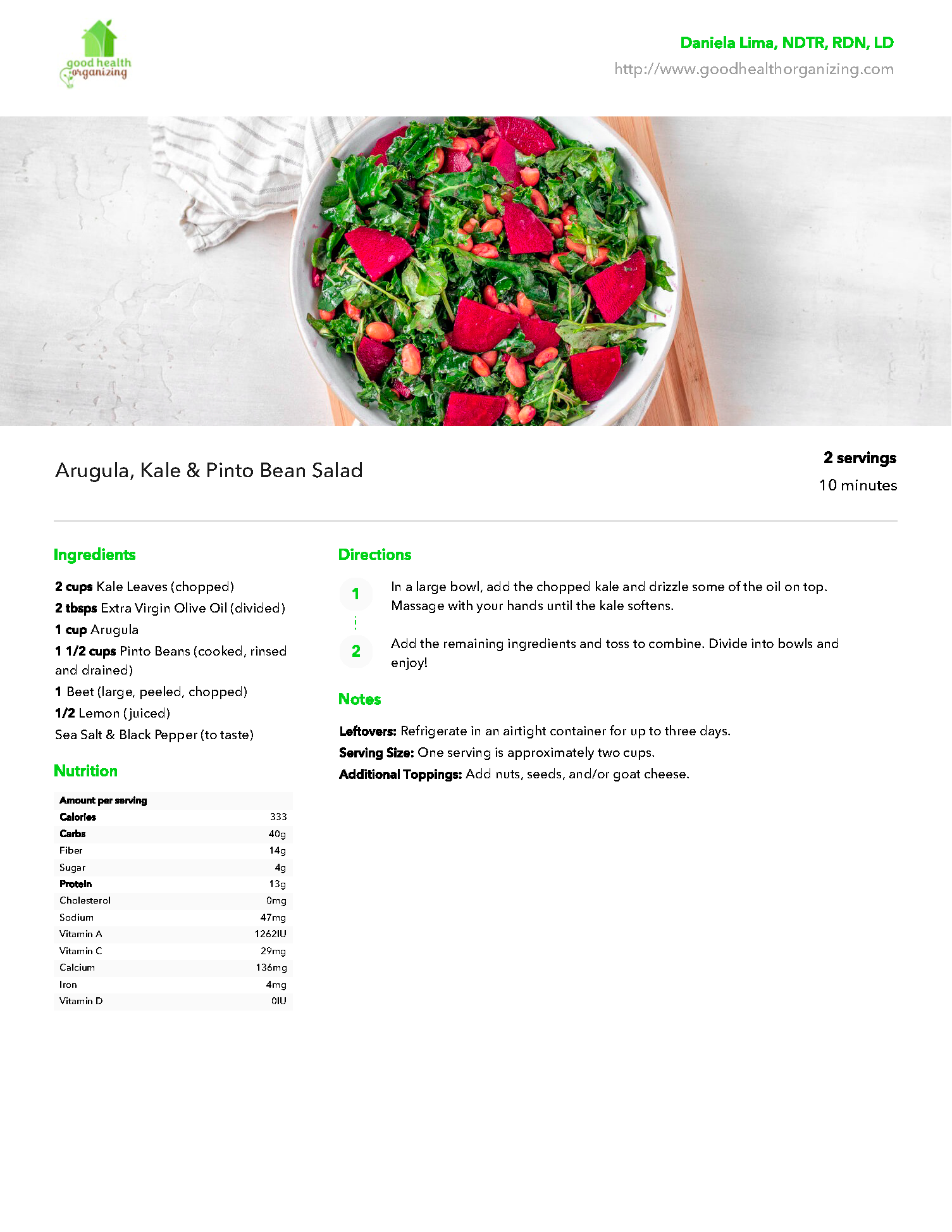 A bowl of salad with strawberries and kale on a wooden cutting board.
