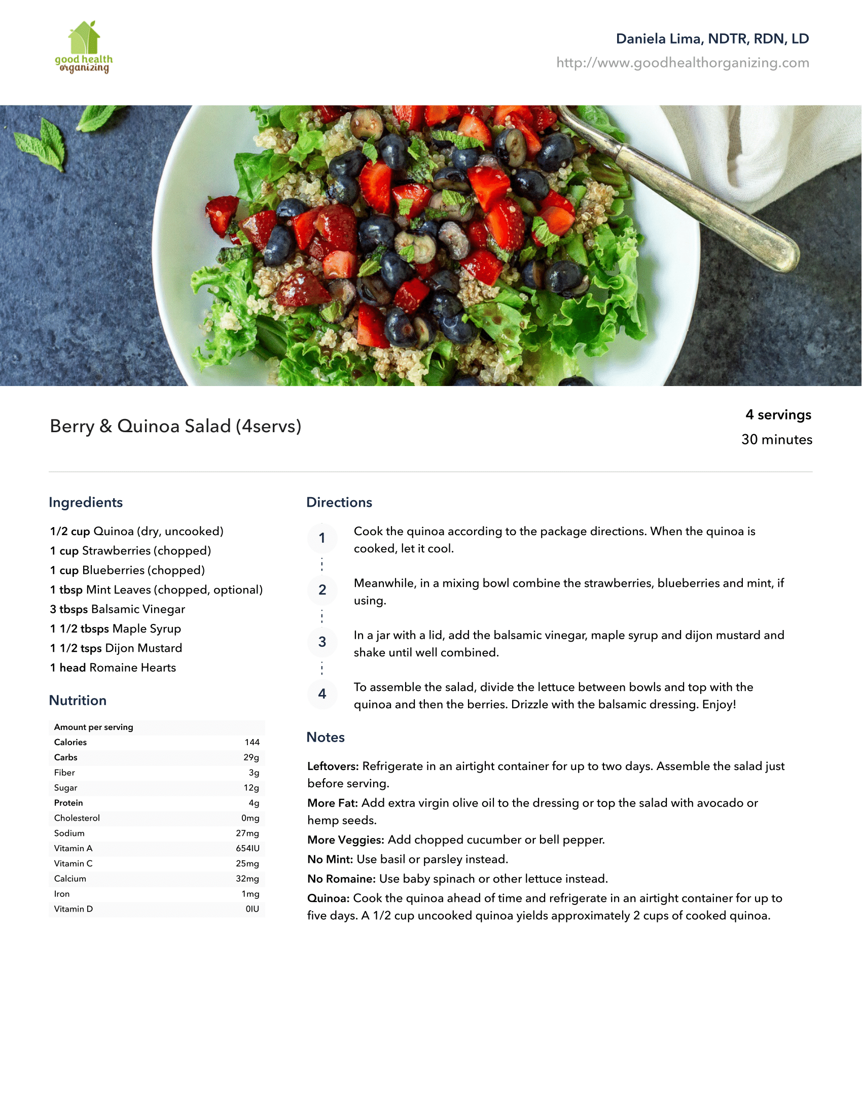 A salad with strawberries , blueberries , and lettuce in a bowl with a spoon.