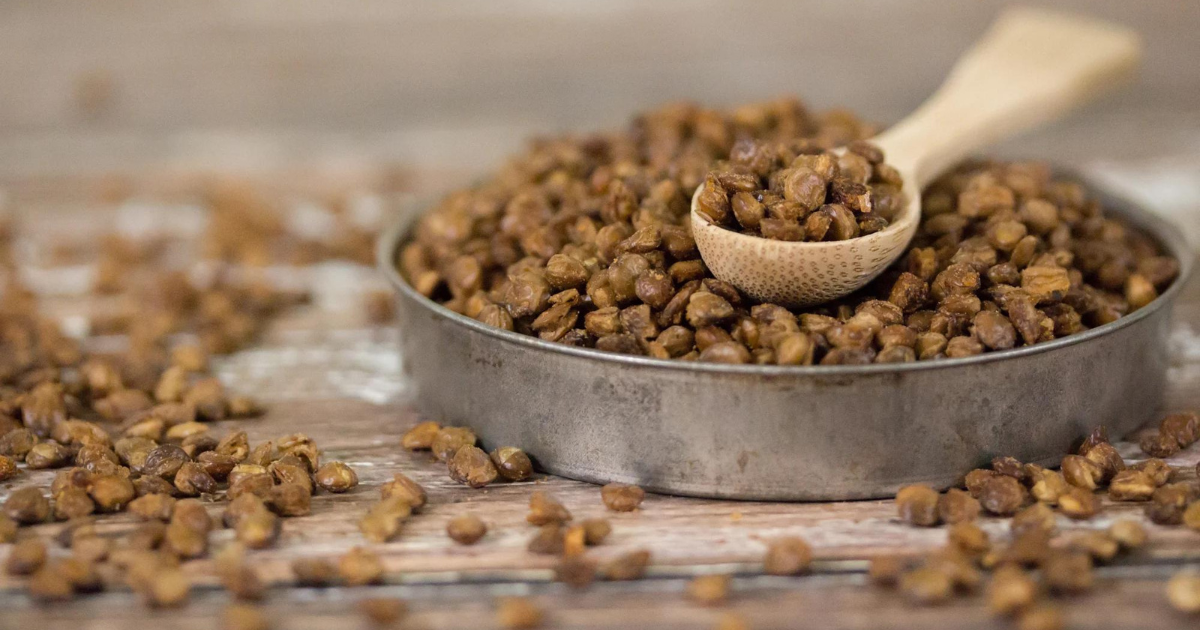 A bowl of roasted lentils with a wooden spoon in it.