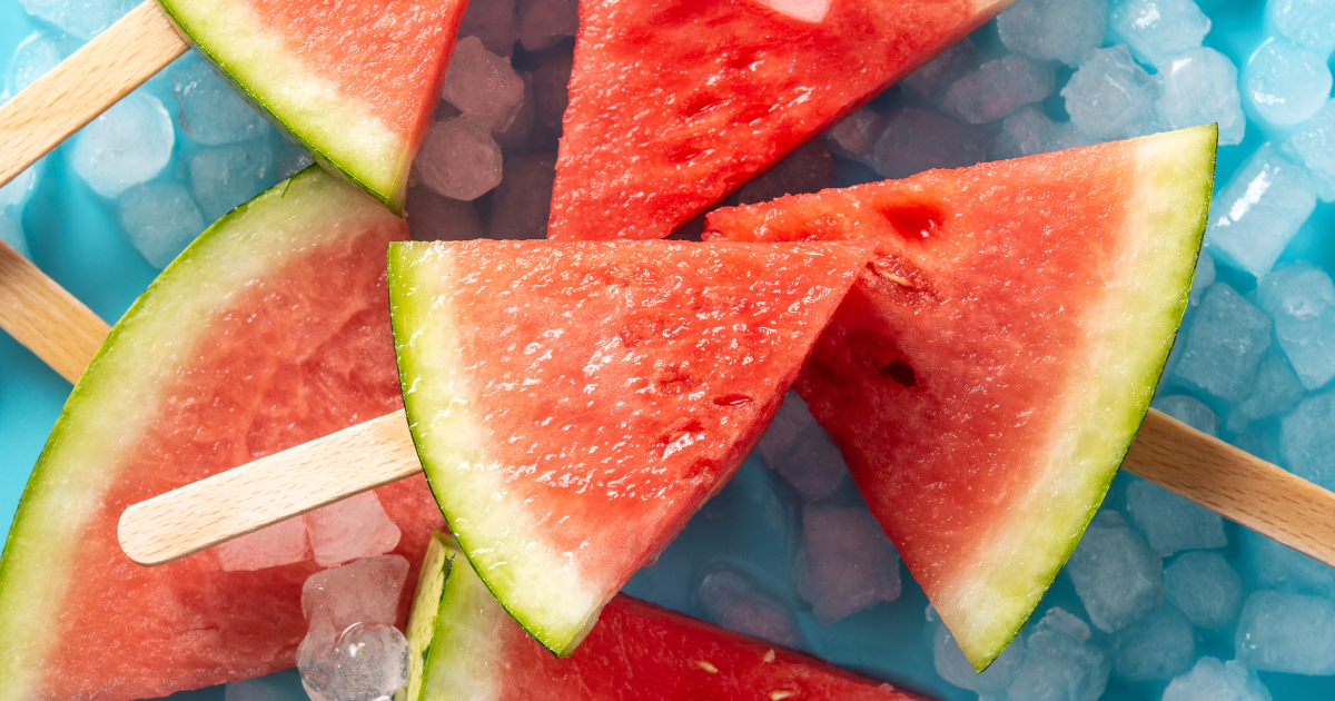 Watermelon slices on sticks on ice on a blue plate.