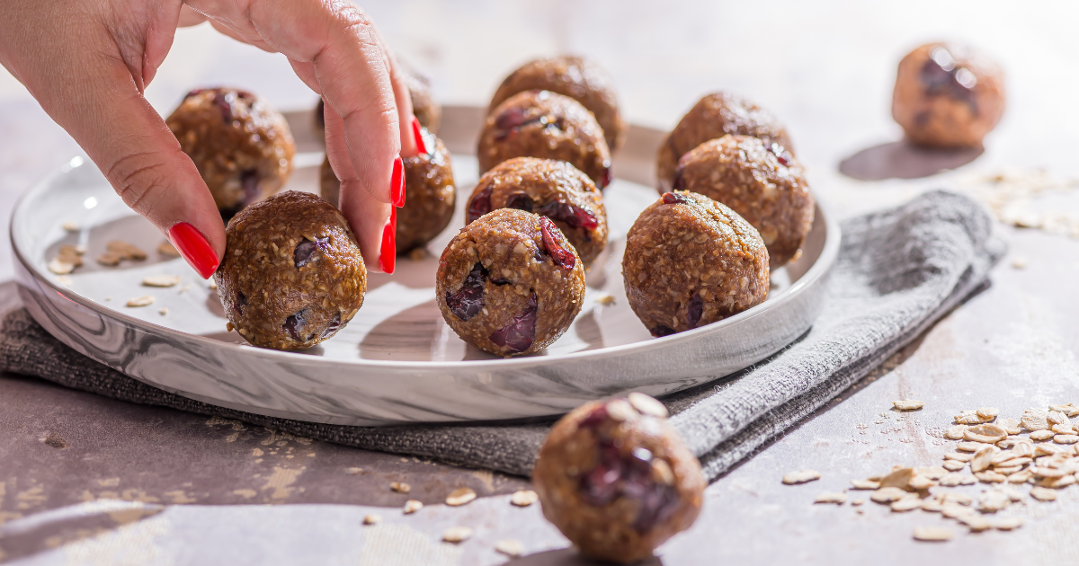 A person is picking up a peanut butter  energy ball from a plate.