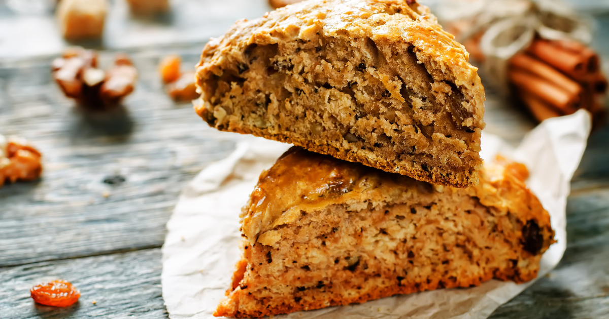 Two pieces of pumpkin cake are stacked on top of each other on a napkin on a wooden table.