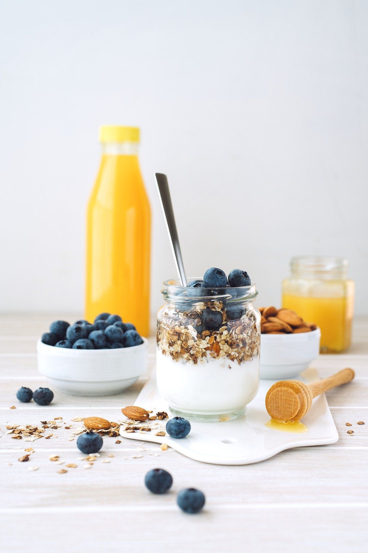 There is a jar of yogurt with blueberries and granola on a table.