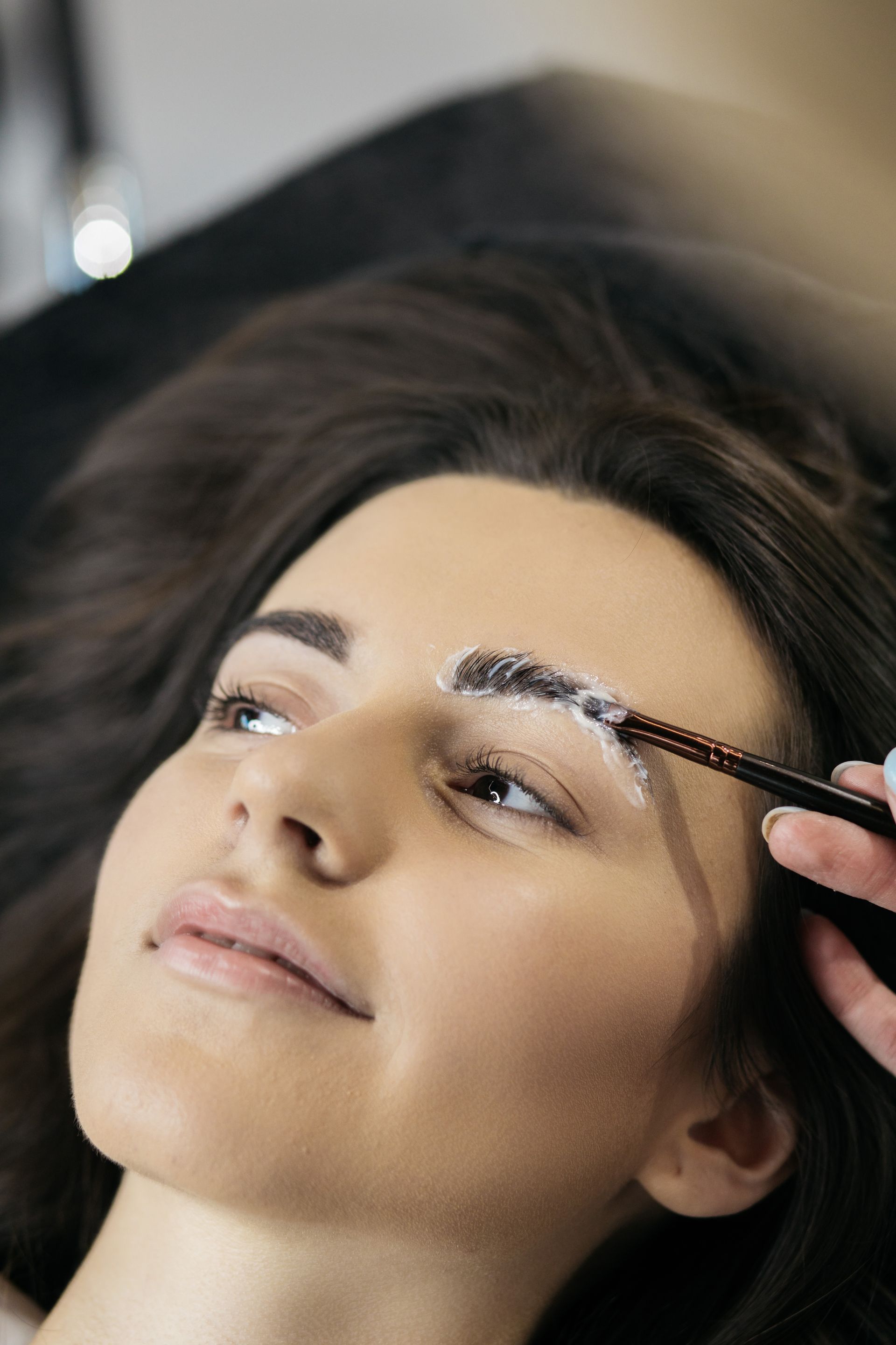 a woman is getting her eyebrows laminated with a brush