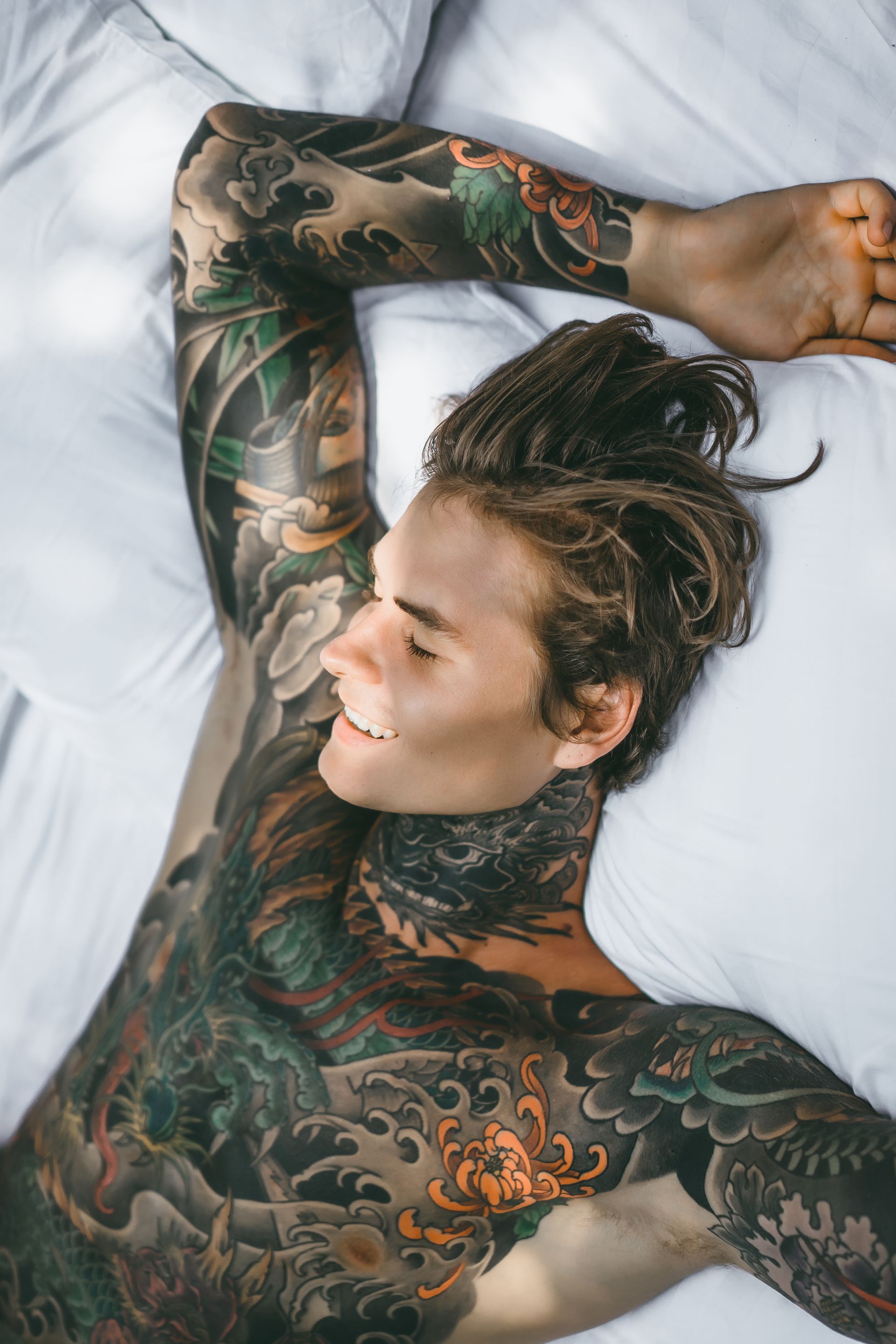 A man with a lot of tattoos on his body is laying on a bed.