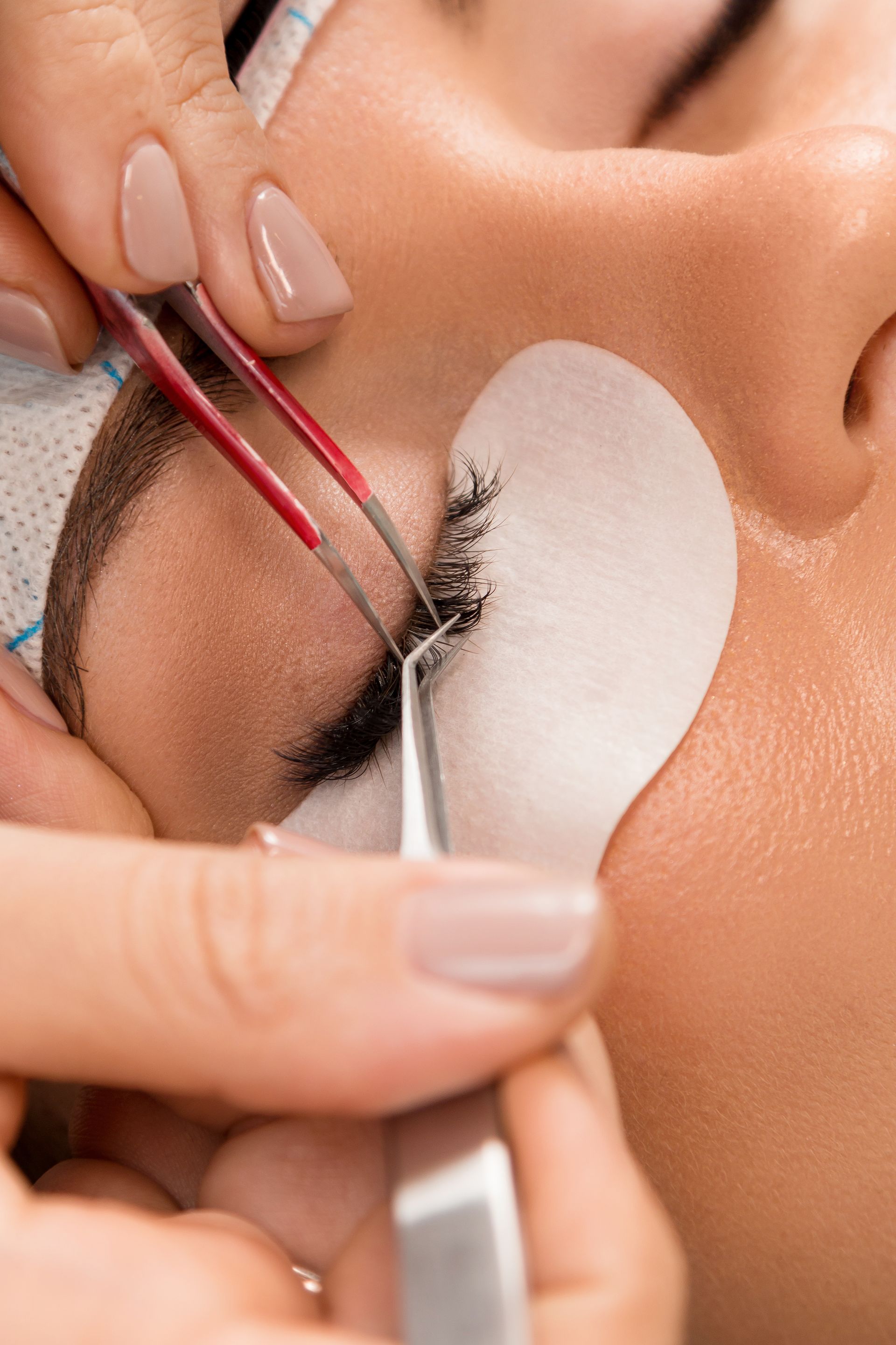 A woman is getting eyelash extensions in a beauty salon.