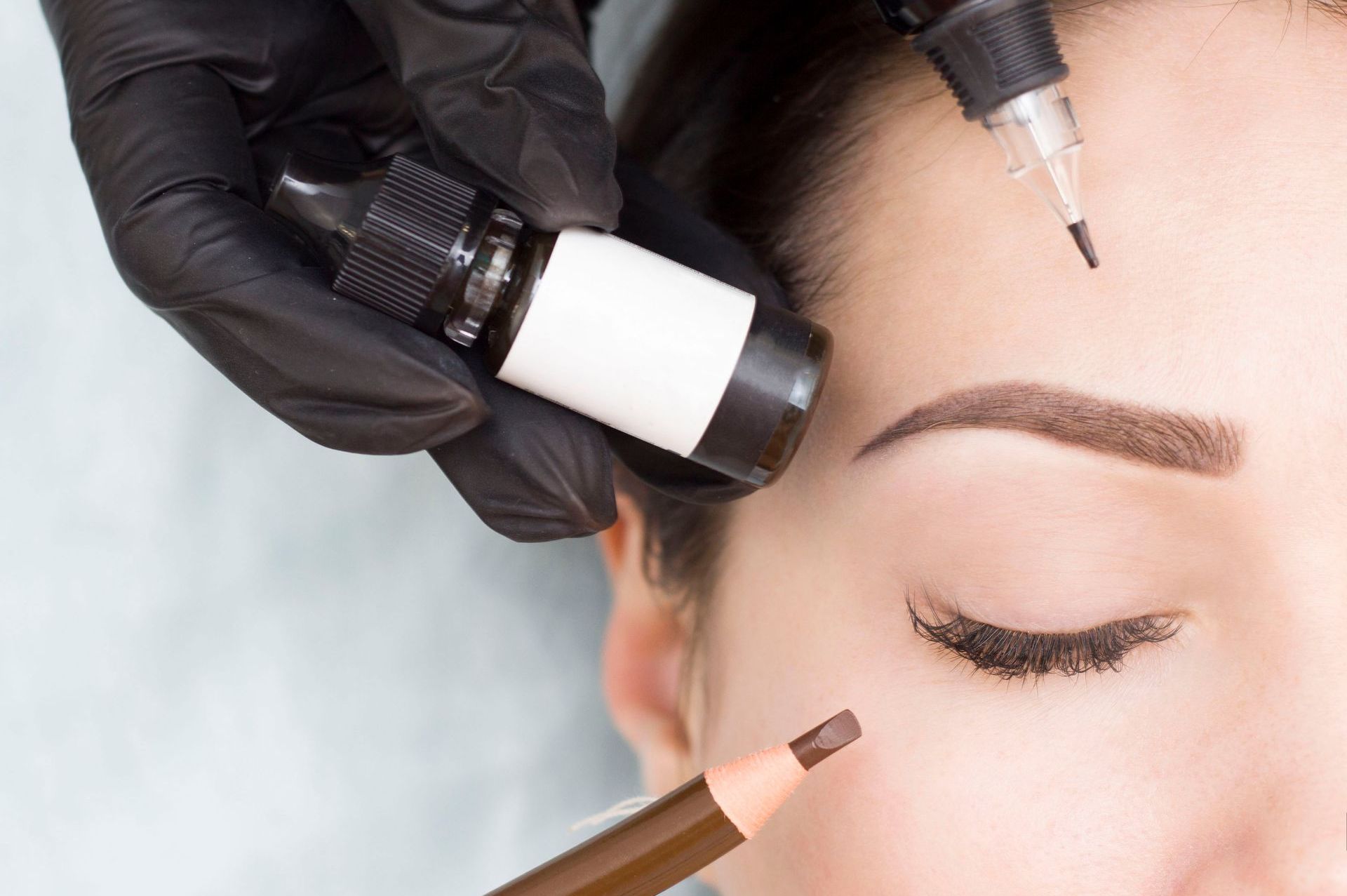 a woman getting her eyebrows painted with a pencil