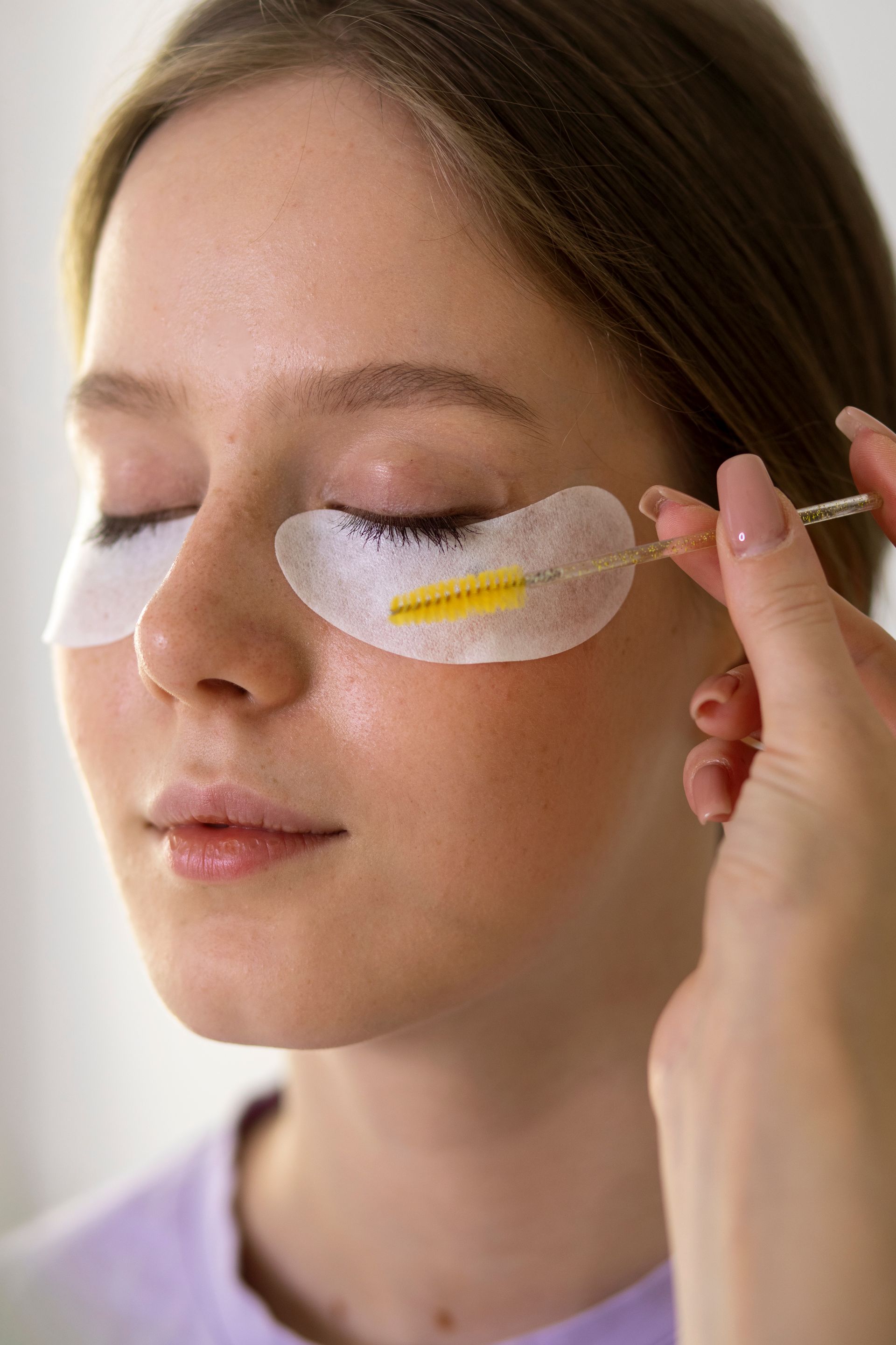 a woman is getting her eyelashes done with a brush