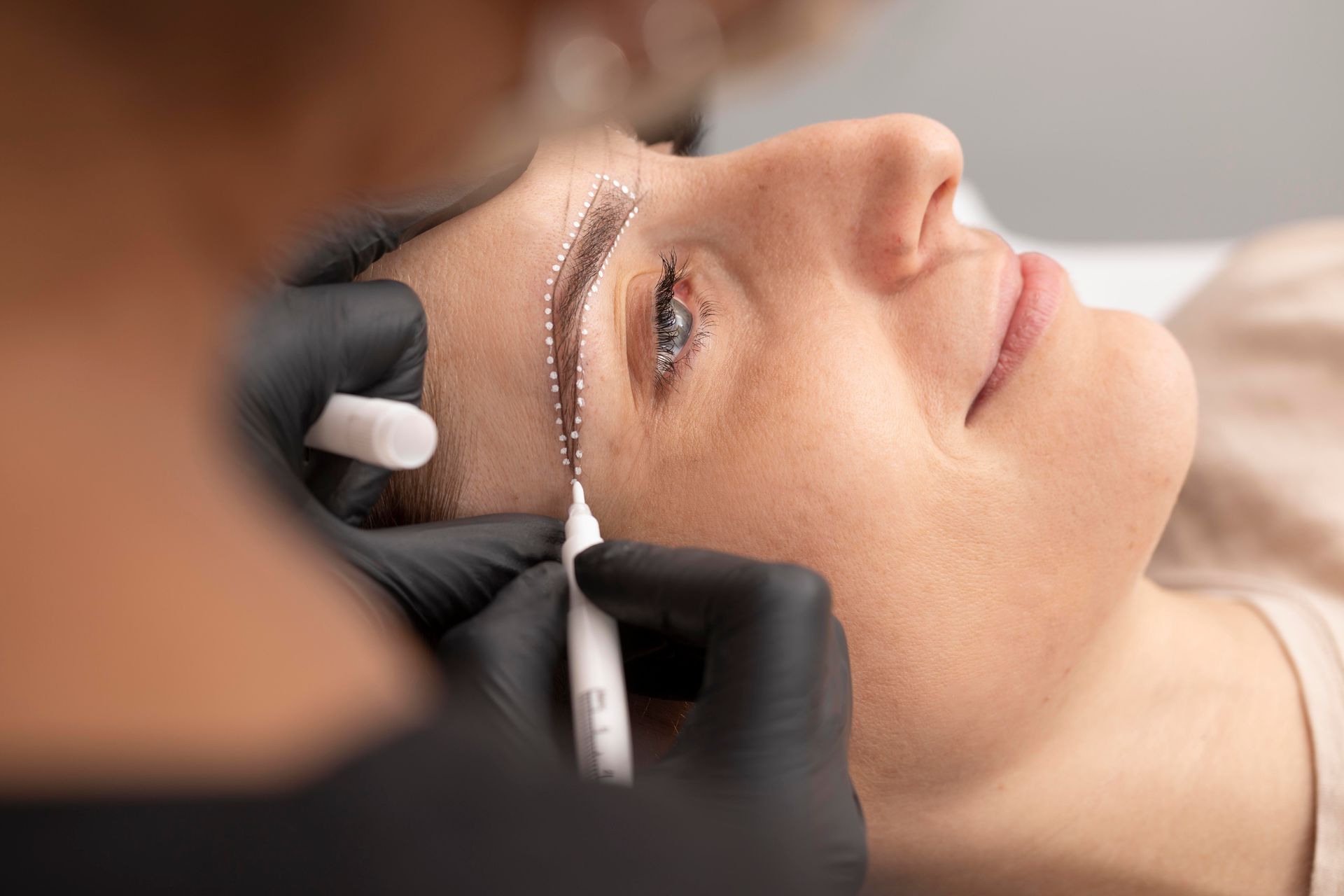 a woman is getting her eyebrows drawn by a makeup artist .