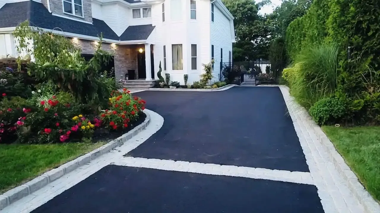 A large white house with a black driveway leading to it.