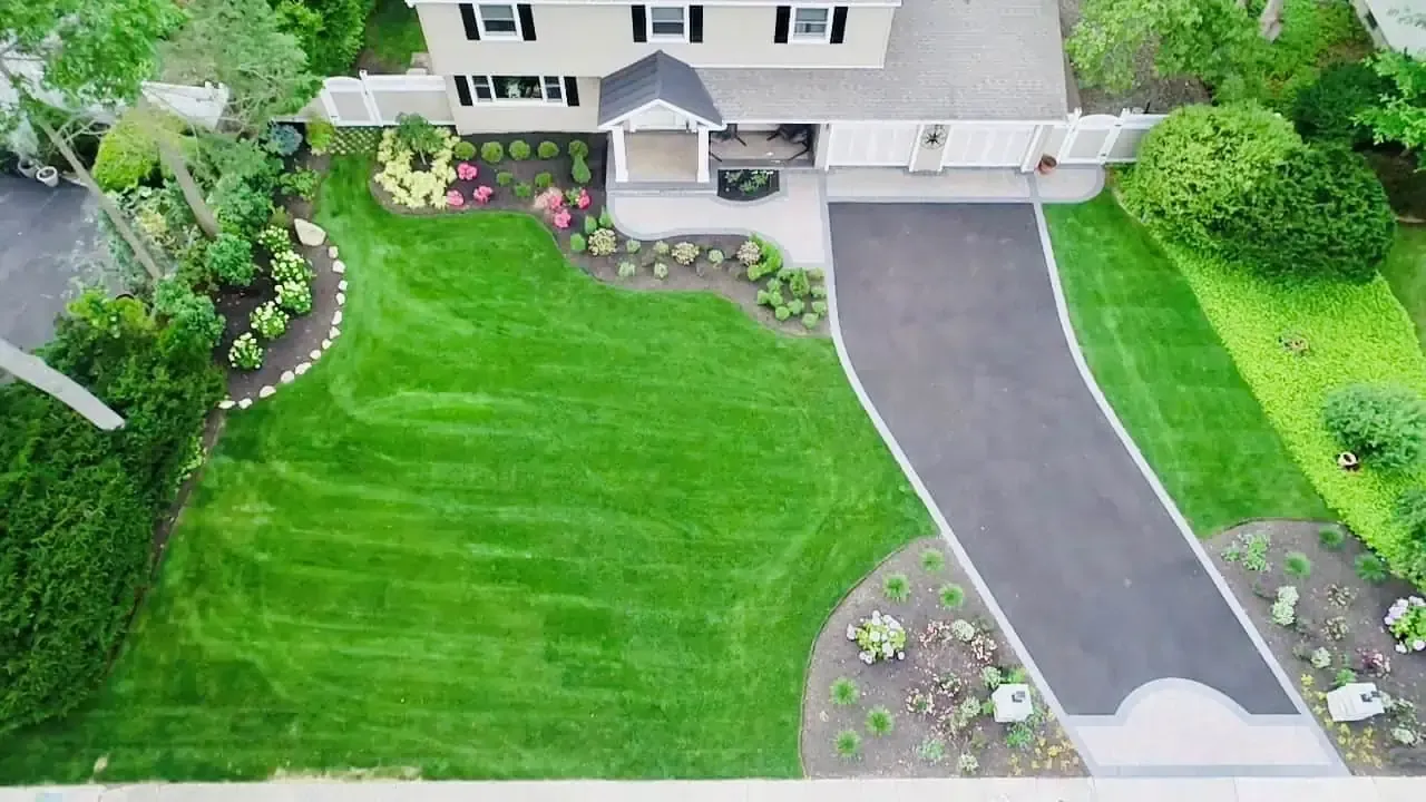 An aerial view of a house with a lush green lawn and a driveway.