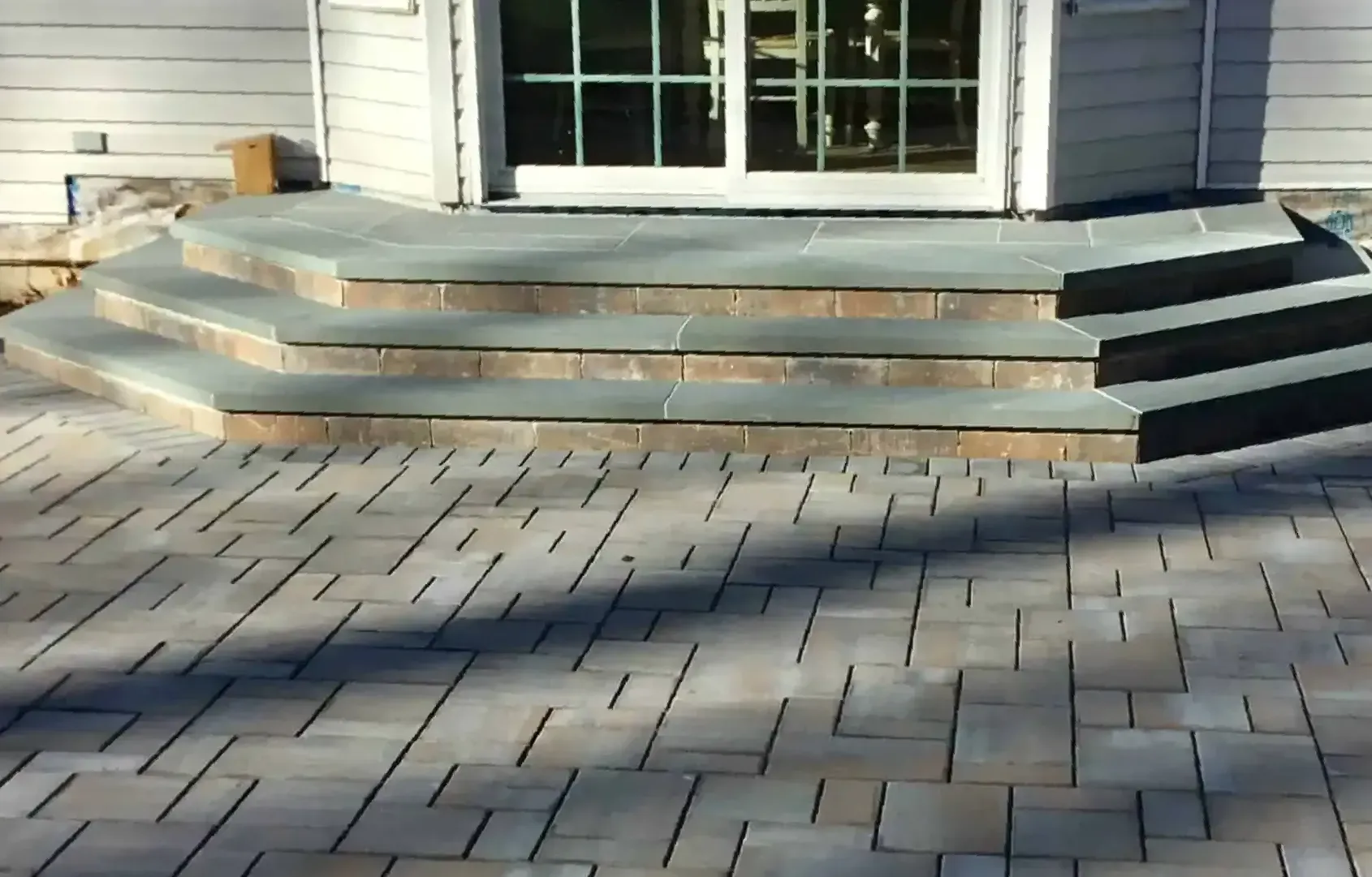 A brick patio with stairs leading up to a door