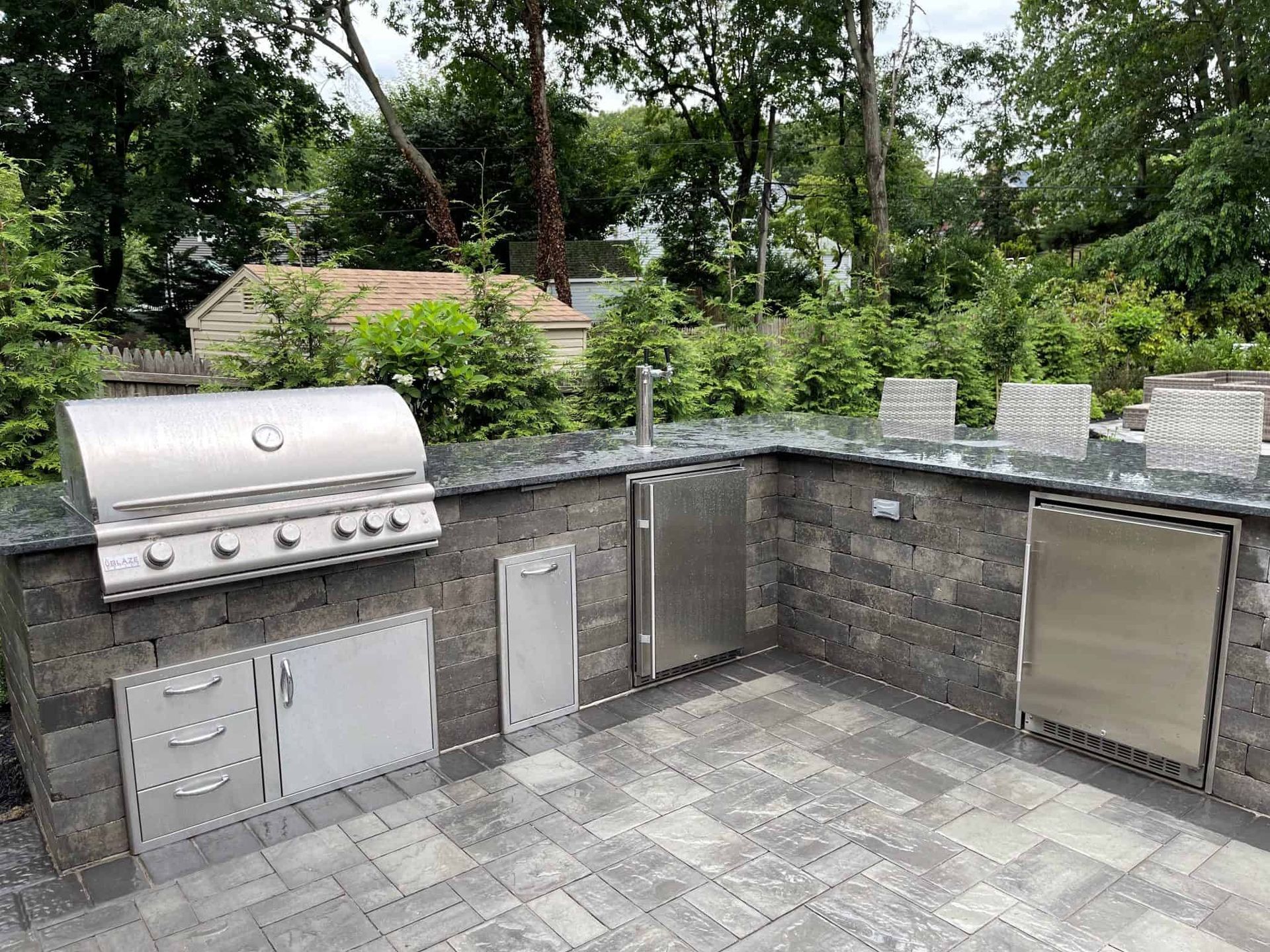 A large outdoor kitchen with a grill and a refrigerator.