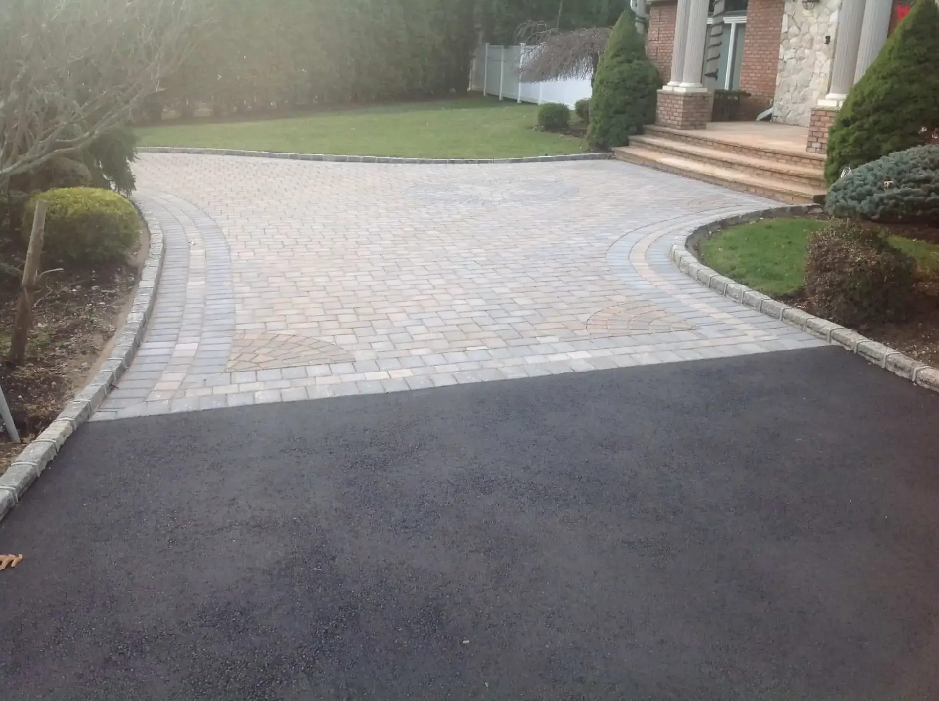A driveway leading to a house with a brick walkway