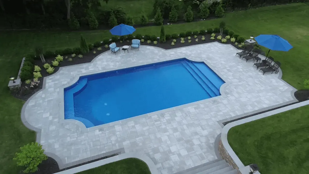 Outdoor Swimming Pool | Libardi Island Landscaping Corp. An aerial view of a large swimming pool surrounded by chairs and umbrellas.
