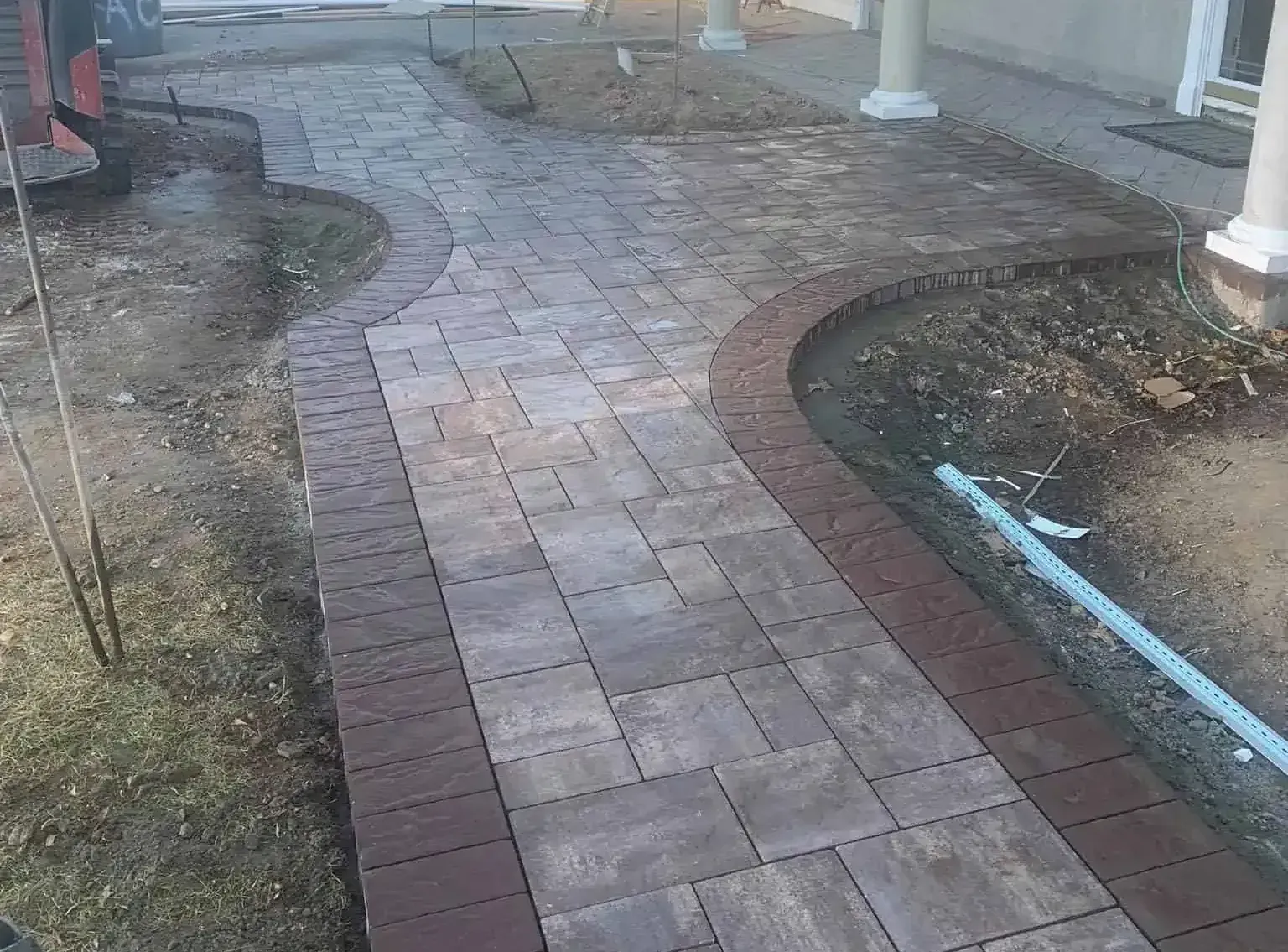 A brick walkway is being built in front of a house.
