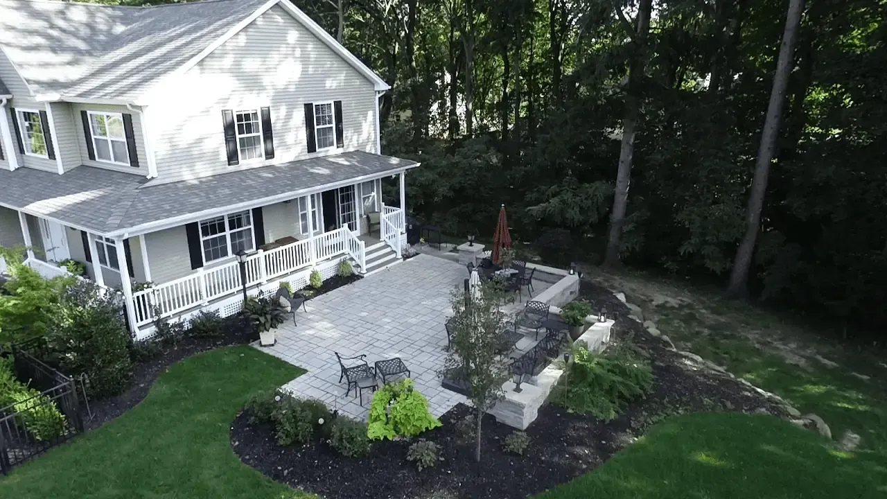 An aerial view of a large white house with a large patio surrounded by trees.