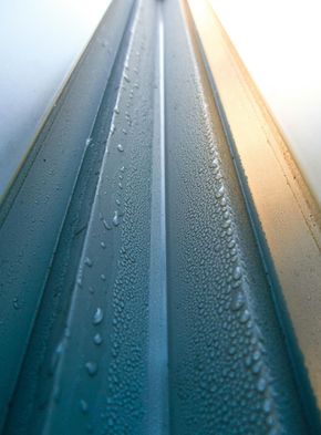 A close-up, angled view of a metal window frame covered in condensation droplets.