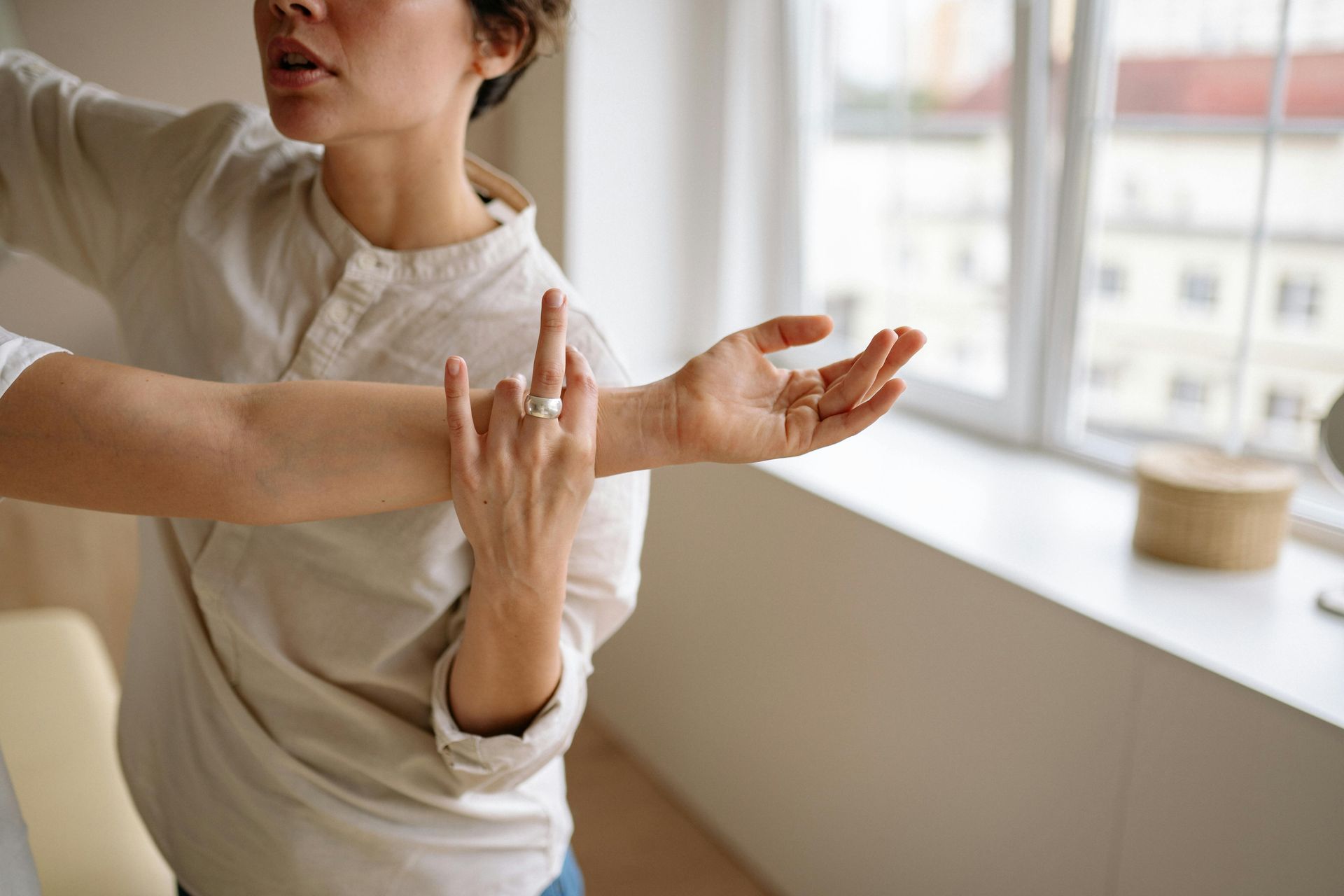 Person reaching arm forward, fingers slightly curved. Wearing ring on hand. Near a window. — Bourbong Street Physiotherapy Centre in Bundaberg West, QLD