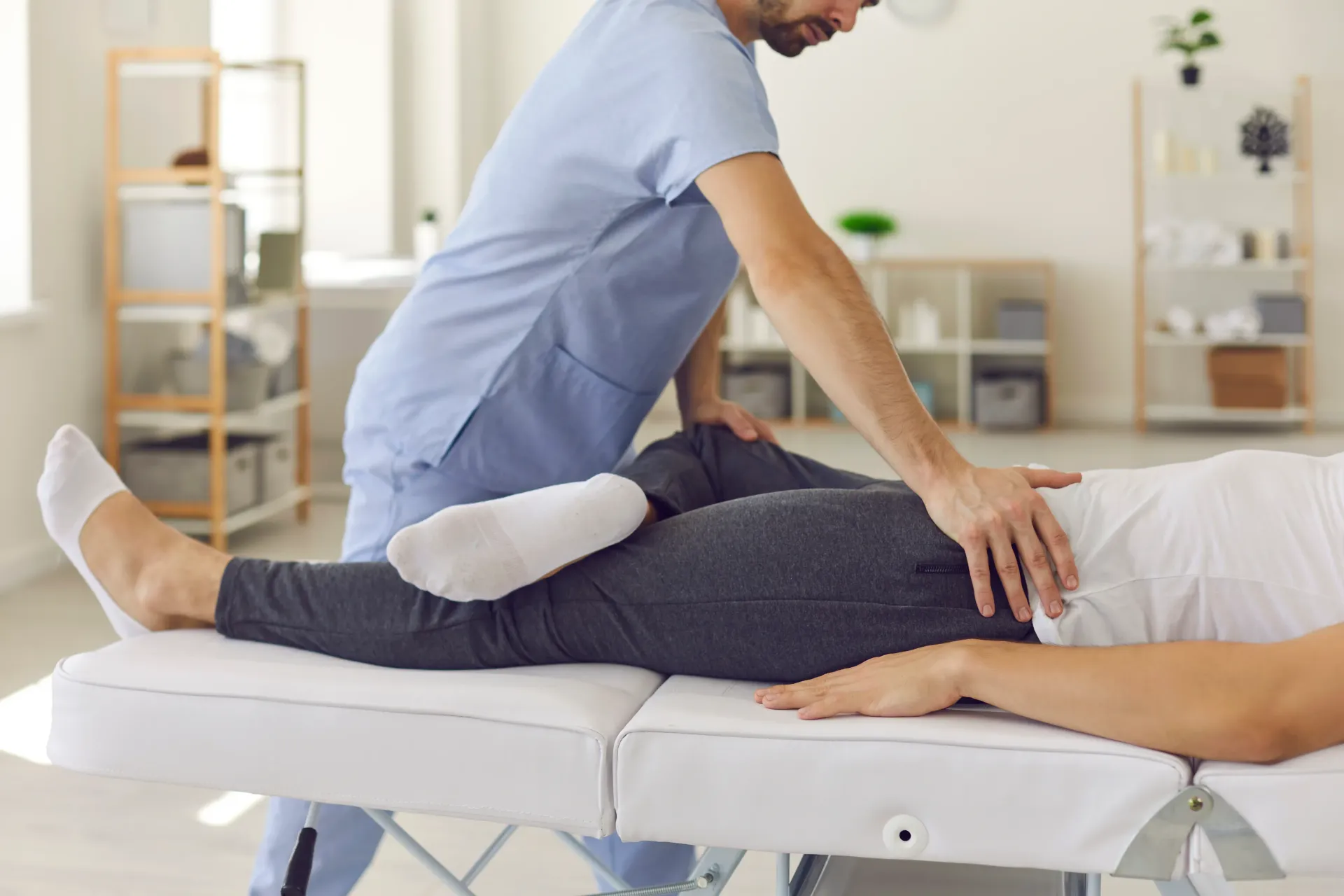Physical therapist manipulating patient's leg on a treatment table. Clinical setting. — Bourbong Street Physiotherapy Centre in Bundaberg West, QLD