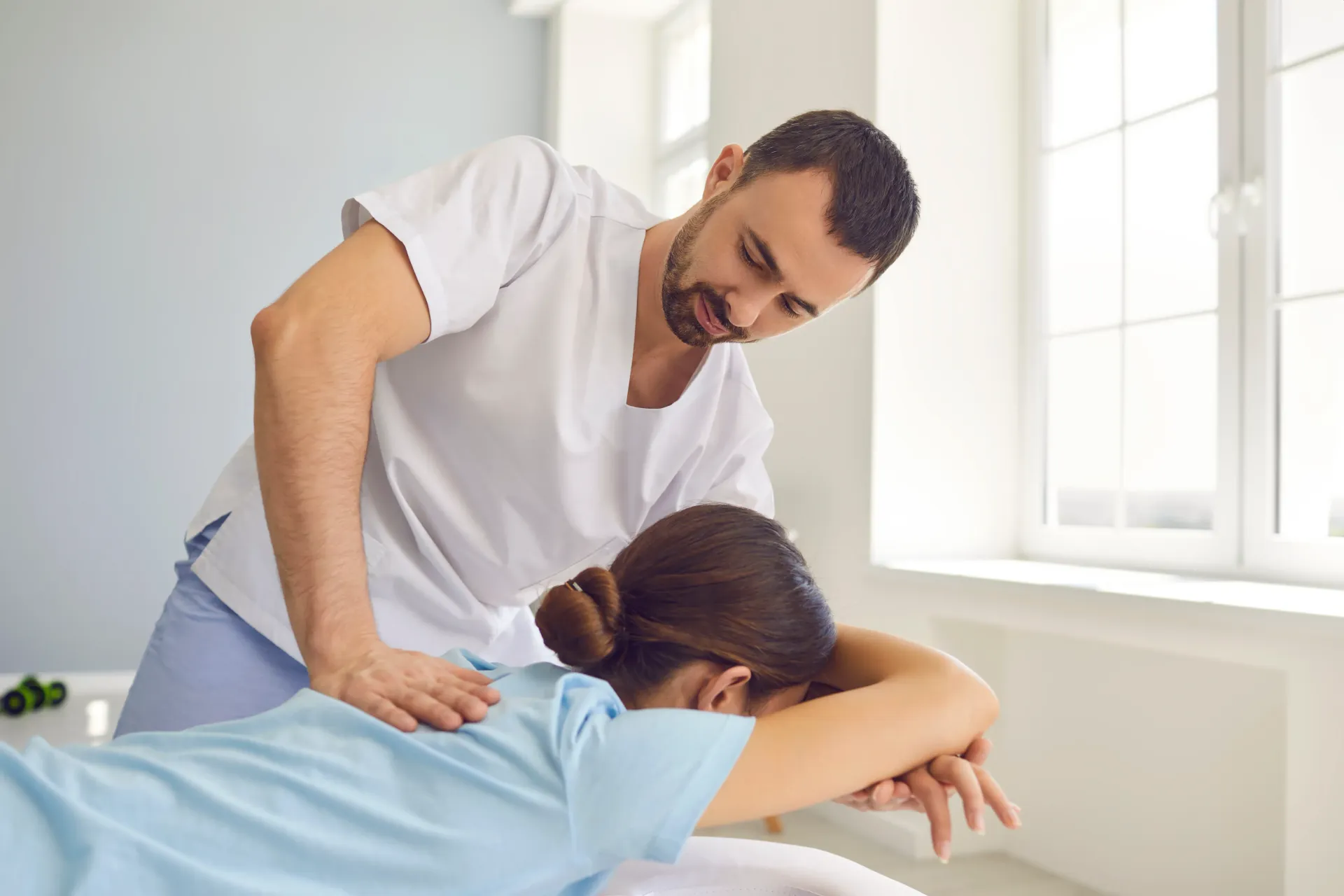 Therapist massaging a person's back. Light-filled room, person lying face down, therapist leaning over them. — Bourbong Street Physiotherapy Centre in Bundaberg West, QLD