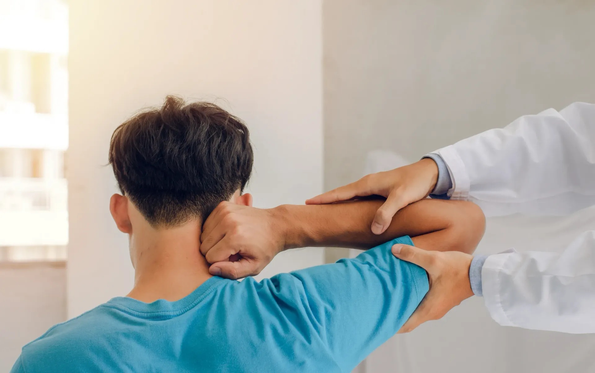 Doctor examining patient's shoulder and neck. Indoor setting, patient in blue shirt. — Bourbong Street Physiotherapy Centre in Bundaberg West, QLD