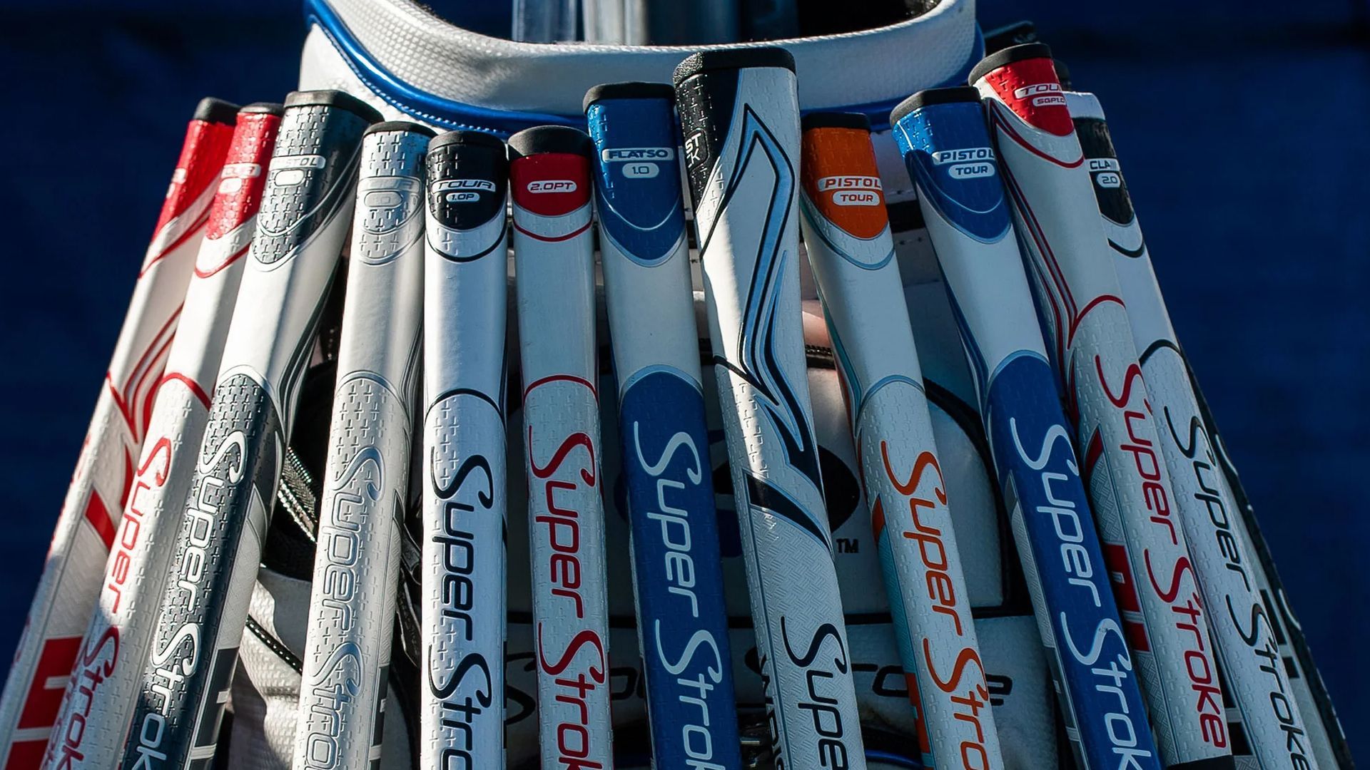 A bunch of super stroke golf clubs are stacked on top of each other