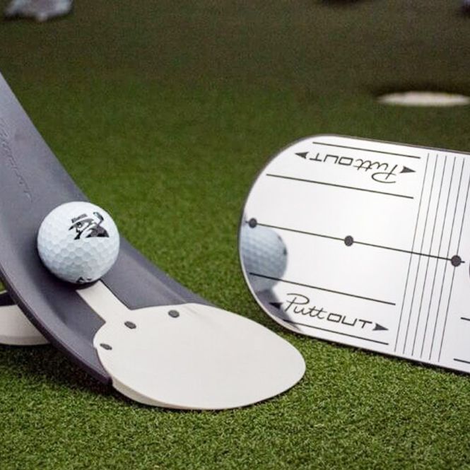 A golf ball sitting on top of a putting board that says putt out