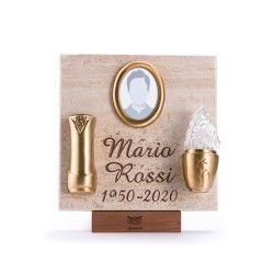 Una targa commemorativa per Mario Rossi (1950-2020) con una cornice ovale per foto, un vaso in ottone e una lampada di cristallo su pietra.