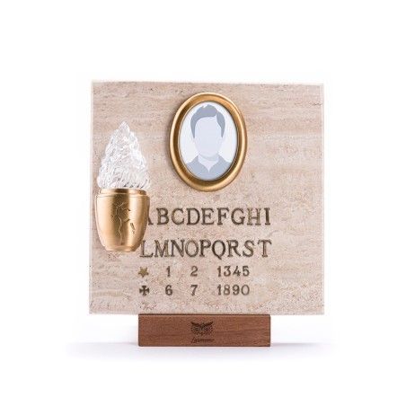 Una targa commemorativa in pietra con una cornice ovale per foto, un portacandele in cristallo e lettere e numeri incisi.