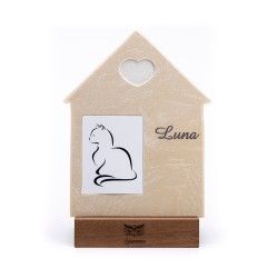 Una targa commemorativa a forma di casa con un intaglio a forma di cuore, un'illustrazione stilizzata di un gatto e il nome