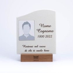 Una targa commemorativa su un supporto di legno, con una foto segnaposto, un testo, le date e una sentita iscrizione in italiano.