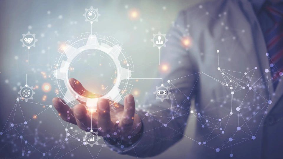 Persona in giacca e cravatta che tiene in mano il simbolo di un ingranaggio luminoso, circondato da connessioni di rete.