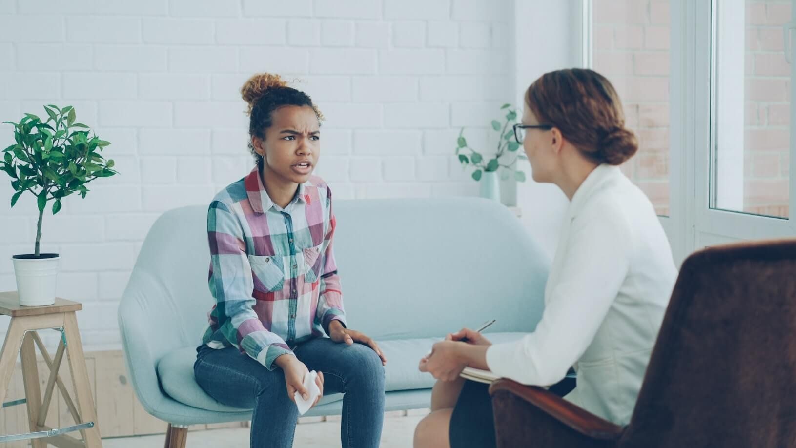 Two people talking in a bright counseling office, seated across from each other.
