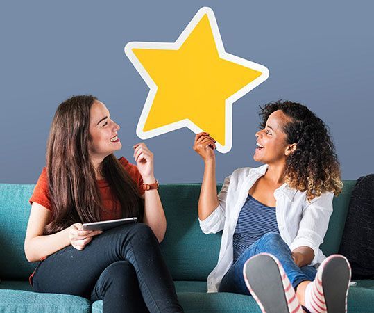 Two people on a couch holding a large yellow star cutout and smiling at each other