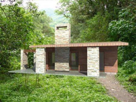Pequeña cabaña moderna de piedra y madera en un claro de bosque frondoso y verde.