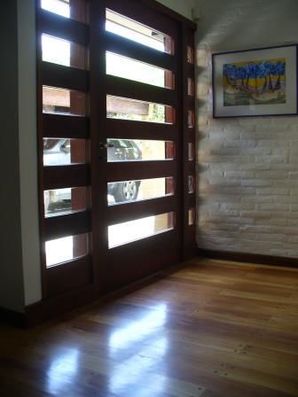Puerta principal moderna de madera con paneles horizontales de vidrio esmerilado, entrada iluminada
