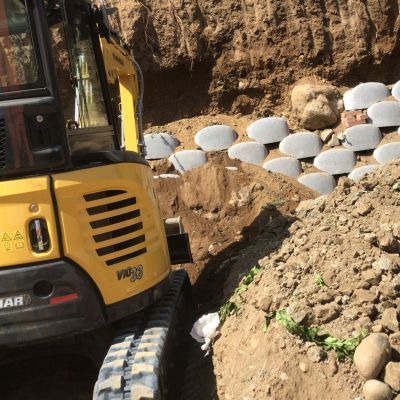 Un escavatore giallo sta scavando una buca nel terreno.
