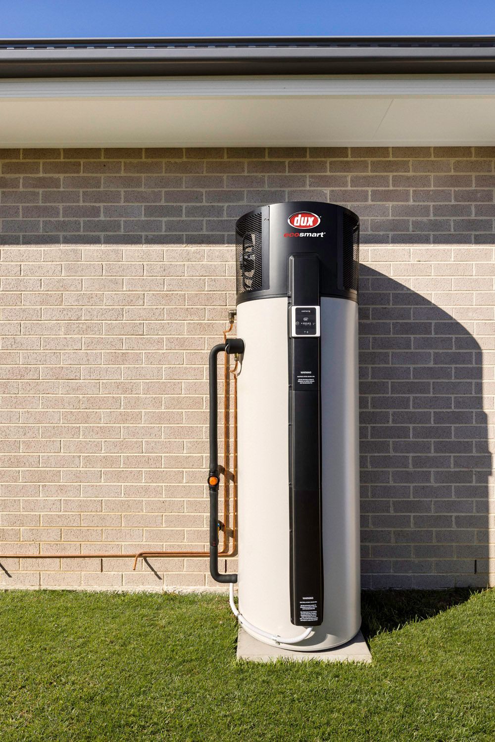 Tall, Cylindrical Hot Water Heater Against a Wall, With Copper Piping and Black Insulation — 24/7 Hot Water in Valdora, QLD