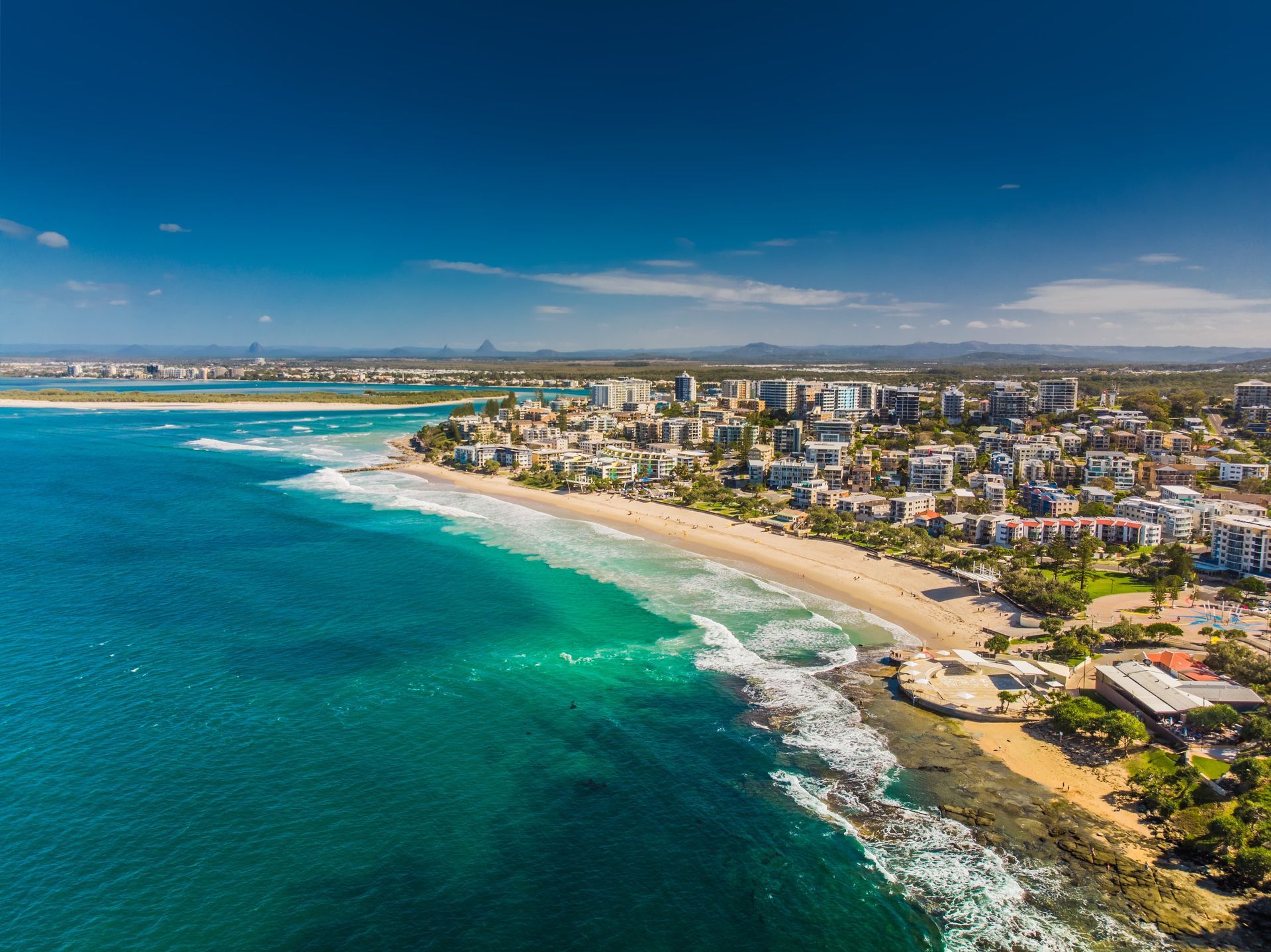 Aerial view of a coastal city with a sandy beach and turquoise water under a blue sky — 24/7 Hot Water in Valdora, QLD