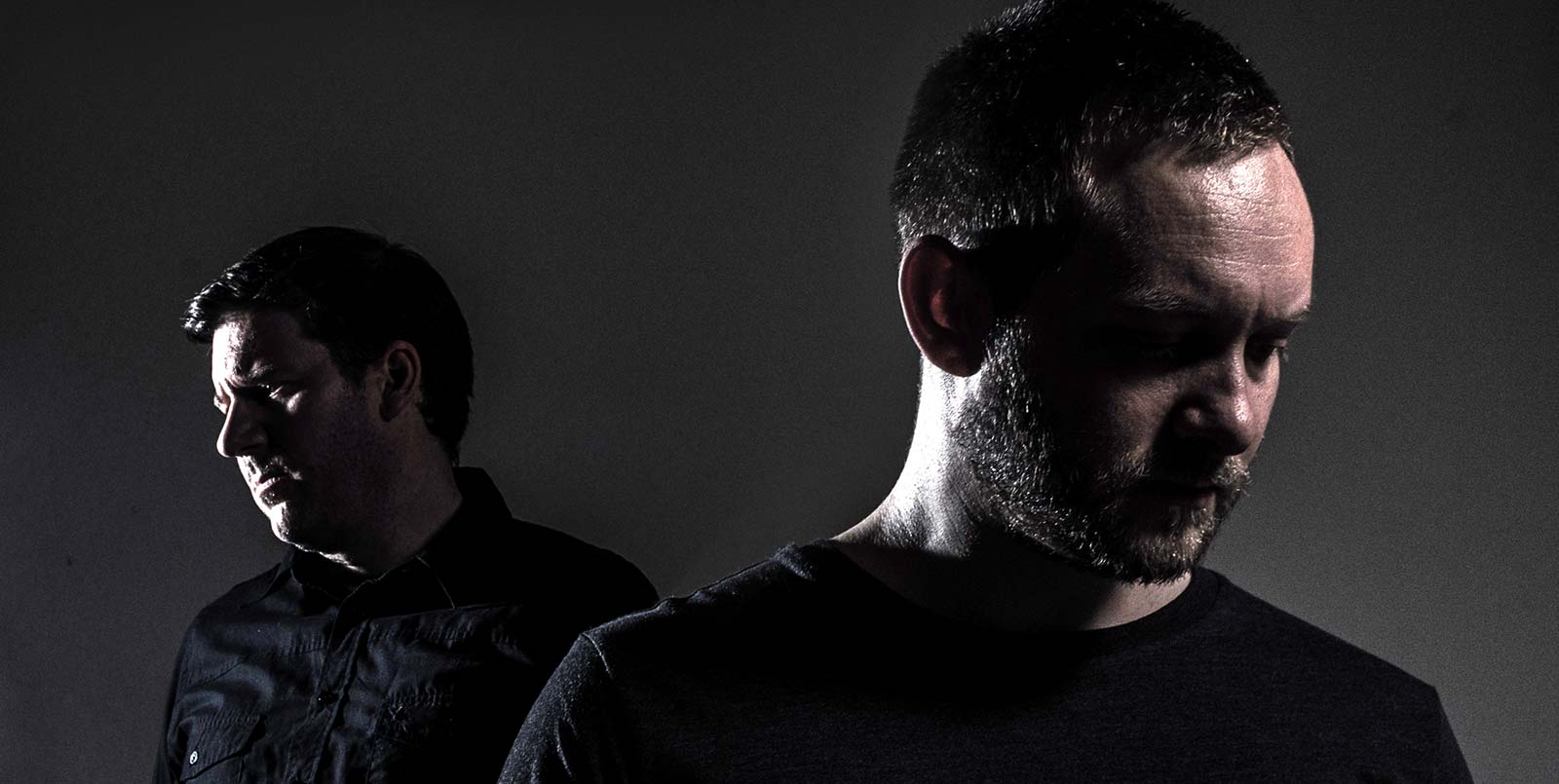 two men are standing next to each other in a dark room .
