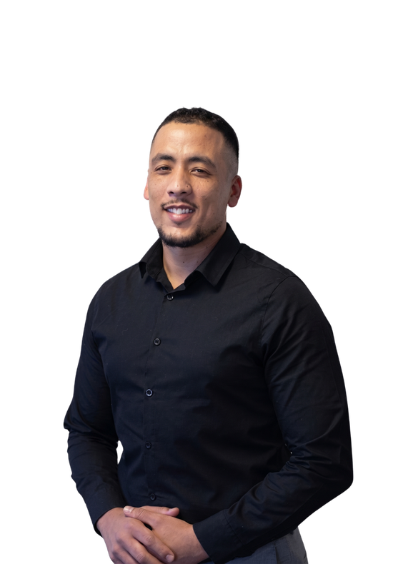 Man in a black dress shirt standing against a white background, hands clasped and smiling.
