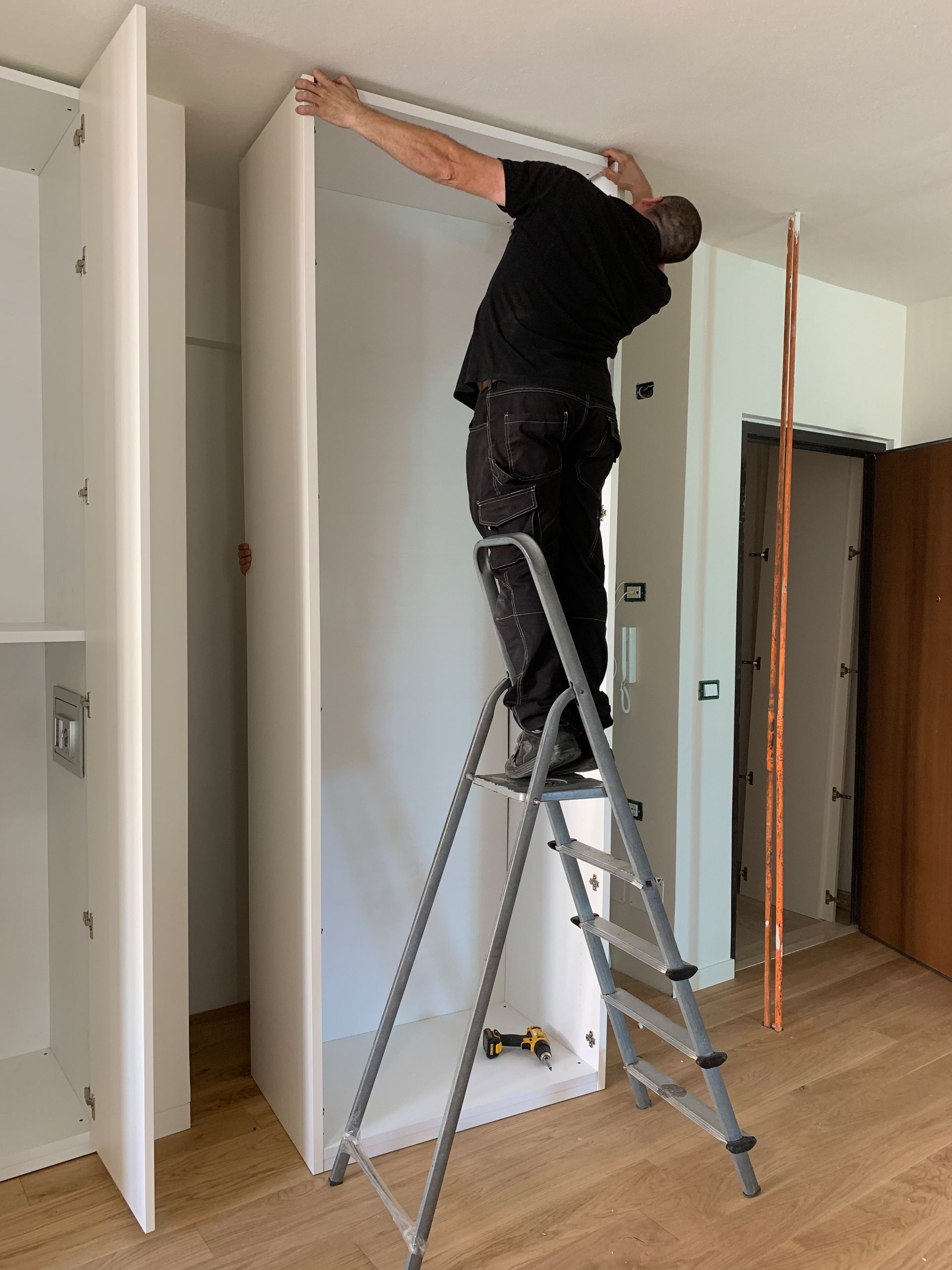 A person in work clothes installing a metal door handle onto a light wood door. A person in work clothes installing a metal door handle onto a light wood door.