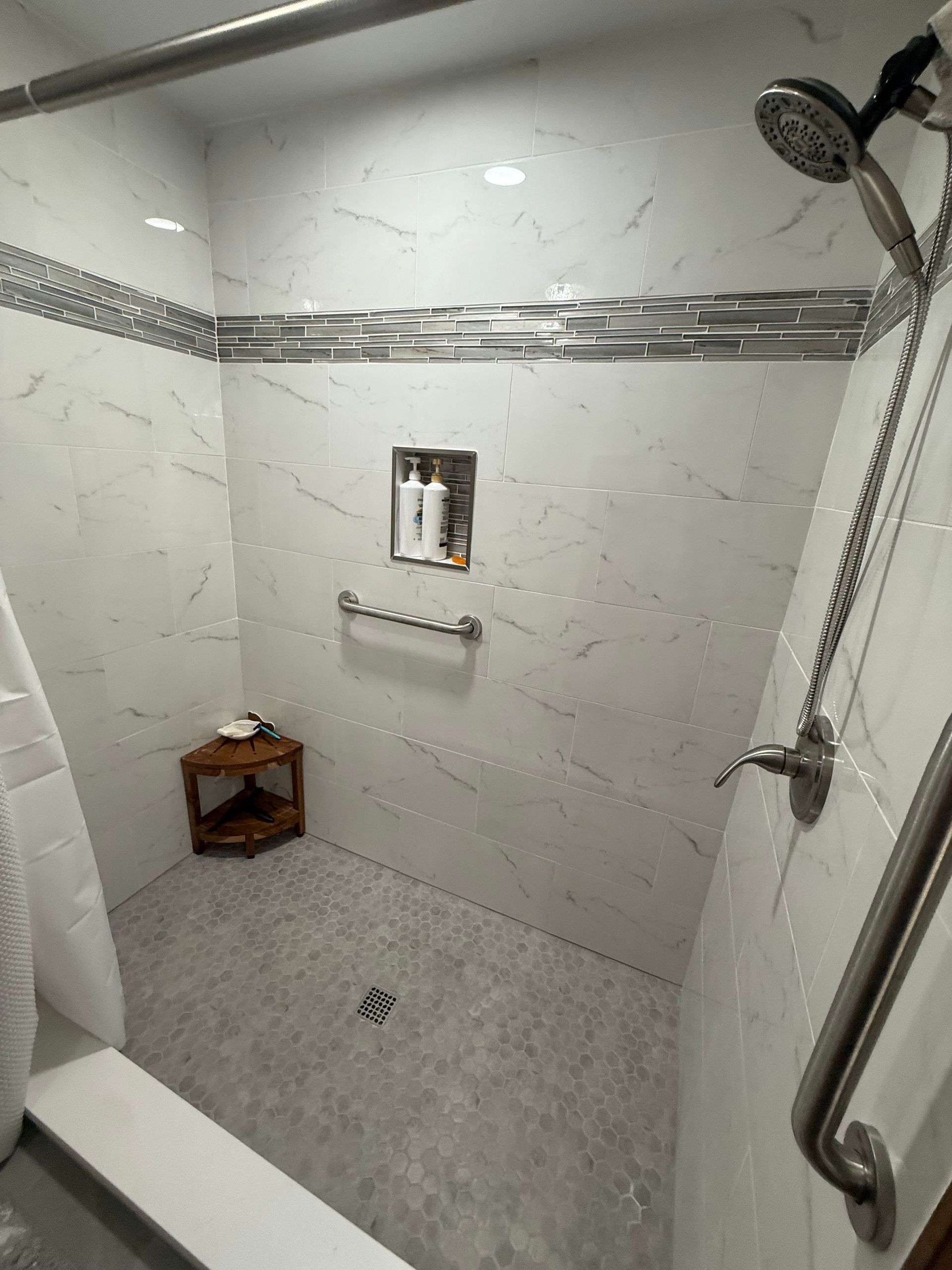 Modern bathroom featuring a white freestanding tub, marble-veined tile flooring, and a large glass-enclosed shower. Modern bathroom featuring a white freestanding tub, marble-veined tile flooring, and a large glass-enclosed shower.