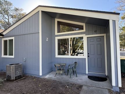 A low-angle view of a sage green, multi-story house with board-and-batten siding against a bright blue sky. A low-angle view of a sage green, multi-story house with board-and-batten siding against a bright blue sky.