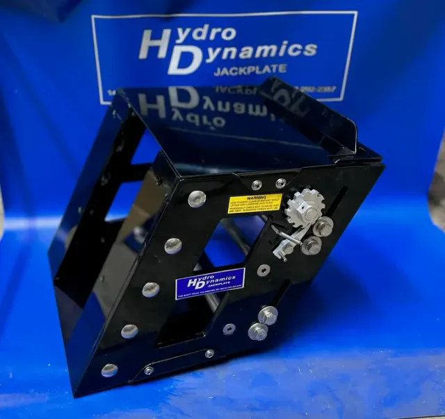 Black Hydro Dynamics jackplate with silver hardware on a blue backdrop, branded sign above.
