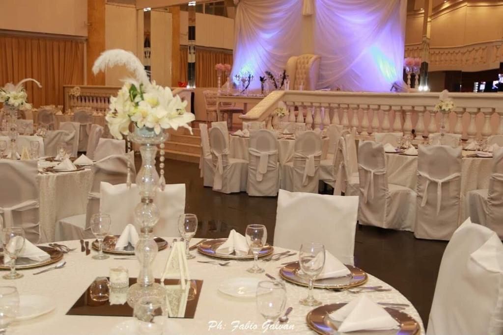 Elegante salón de banquetes con mesas redondas, fundas blancas para las sillas y centros de mesa florales.